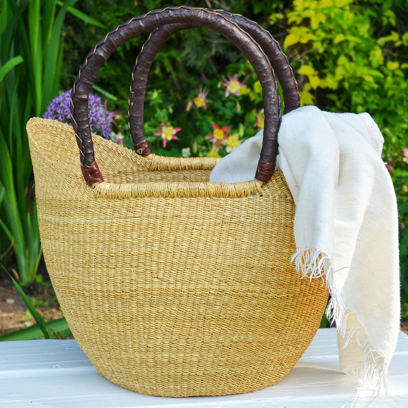 This image showcases a beautifully handwoven shopper bag made from natural fibers, featuring sturdy leather handles for durability and style. The natural tone adds elegance, making it perfect for daily errands or as a chic accessory for the farmer's market.