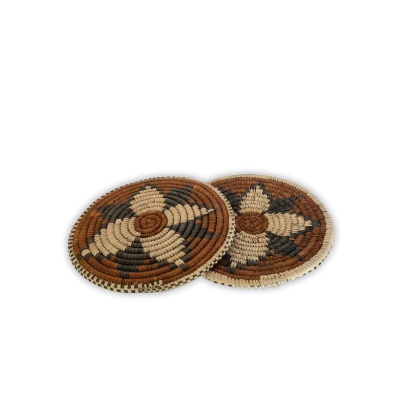 Handwoven natural fiber trivet featuring an earthy geometric pattern in black, tan, and cream tones. Perfect for protecting surfaces while adding artisan charm to your kitchen or dining area.