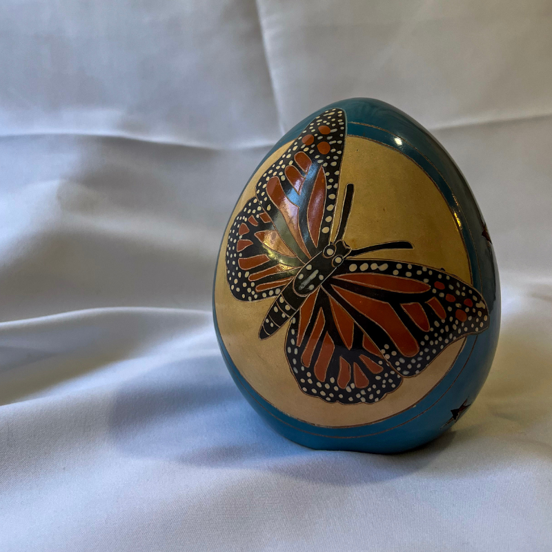 Handcrafted ceramic luminary featuring a vibrant butterfly design, set against a soft white background, showcasing its intricate artistry and warm glow potential.