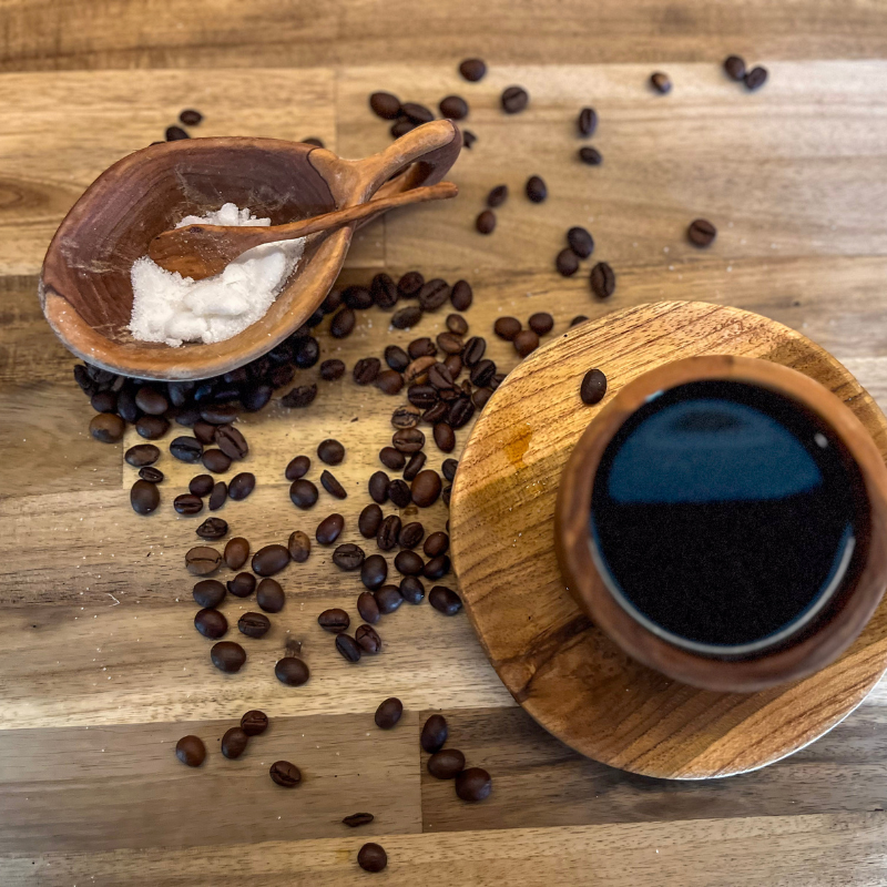 Handcrafted wooden spice bowl with a matching spoon, filled with sugar, paired with a wooden coffee cup on a rustic wooden surface, surrounded by scattered coffee beans for a cozy, natural vibe.